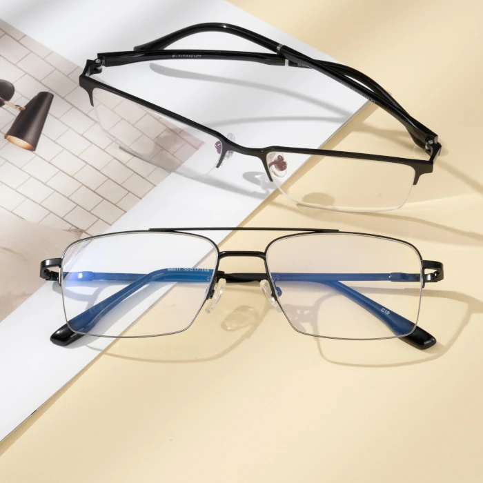 Two half frame black spectacles on top of a table and paper